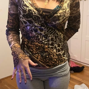 Mönstrad omlottopp från CMD - Snygg mönstrad omlottopp från CMD i storlek S. Toppen har långa ärmar och ett unikt mönster i jordnära färger som brunt och beige. Perfekt för att ge en bohemisk touch till din outfit.