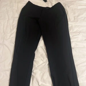 Svarta kostymbyxor från Zara - Snygga svarta kostymbyxor från Zara i en klassisk design. Byxorna har en rak passform och är perfekta för en stilren look. De är tillverkade i ett bekvämt material och har en diskret dragkedja framtill.