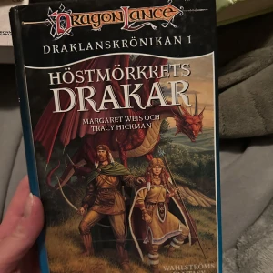 Höstmörkrets Drakar - Boken 'Höstmörkrets Drakar' är den första delen i Draklanskrönikan av Margaret Weis och Tracy Hickman. Omslaget visar två karaktärer och en drake i en fantasymiljö. Perfekt för fantasyälskare som vill dyka in i en episk berättelse.