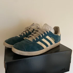 Adidas Gazelle  - Snygga Adidas Gazelle sneakers i blå mocka med vita detaljer och snörning. Hyfsat använda men fortfarande mycket liv kvar storlek 41 1/3!