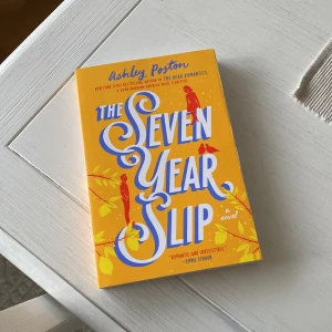 The Seven Year Slip - En roman av Ashley Poston med en färgglad gul och blå omslagsdesign. Boken handlar om kärlek och tidens gång, med en berättelse som utspelar sig på samma plats men vid olika tidpunkter. Perfekt för dem som gillar romantiska och magiska berättelser. Sprillans ny och oläst! 