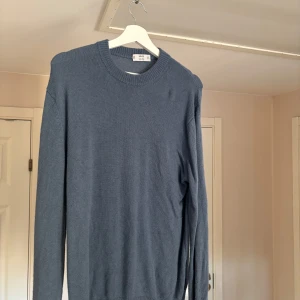Blå tröja från MNG - Säljer en stilren blå tröja från MNG, tillverkad av italienskt garn. Tröjan har en klassisk rund hals och långa ärmar. Knappt använd då den inte satt bra på mig (för liten) köpt för något år sen för 799kr. Köpare står för frakt