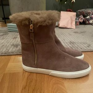 Ralph lauren mocka boots med päls NYSKICK - Snygga brun/beige boots i mocka med mjuk pälsdetalj upptill och dragkedja i guld på sidan. Perfekta för kyliga dagar med en bekväm vit sula.