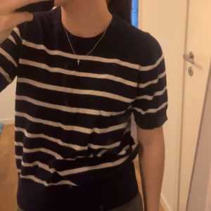 Stickad kortärmad - Stickad kortärmad tröja som är marinblå med vita ränder. Den är i storlek s, används väldigt sällan så därför säljer jag den.