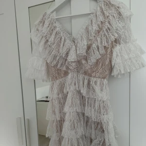 Vit spetsklänning från By Malina!💗 - Säljer en vit spetsklänning från By Malina med volanger och v-ringad design. Klänningen har korta ärmar och flera lager av spets som ger en elegant look. Perfekt för speciella tillfällen!💗 Säljer den för att jag inte kommer använda den mer, hör av er om ni är intresserade!❤️