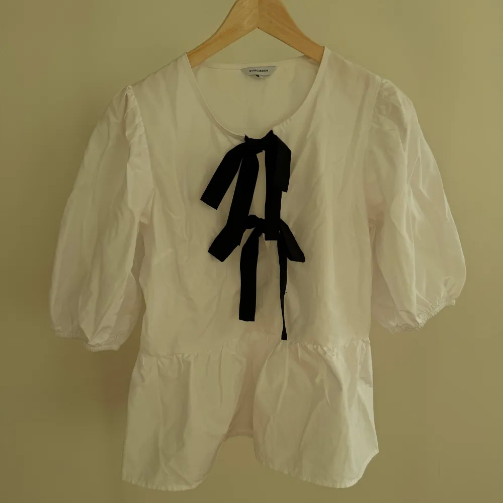 Söt blus med två svarta rosetter. Rekommenderar att man stilar men en jeans eller svart kjol. Har bara haft den på mig några gånger.. Puserot.