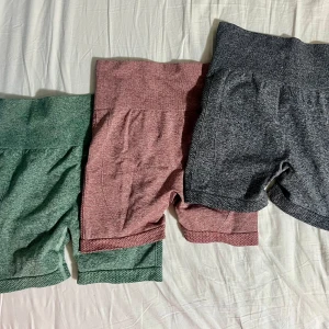 Träningsshorts i tre färger - Säljer tre par träningsshorts i grönt, rosa och grått. De är högmidjade och har en tight passform med ribbade detaljer. Dom har även en scrunch där bak för att ge illusionen av en större rumpa. Perfekta för gymmet eller yoga!