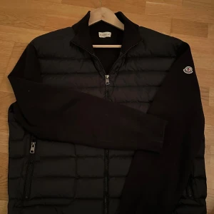 Moncler cardigan🍾 - Snygg svart jacka från Moncler med quiltad design och dragkedja framtill. Jackan har långa ärmar och ett broderat Moncler-märke på armen. Ny pris 10 150kr. 