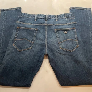 Blå jeans från Armani - Snygga blå jeans från Armani. Perfekta för en stilren look med en touch av lyx. Märkeslogga på bakfickan ger en exklusiv känsla. Storlek W33. Använd men i mycket bra skick