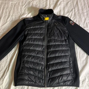 Parajumper warm up L - Säljer en svart jacka från Parajumpers i herrstorlek L. Den har en quiltad design med dragkedja och en cool patch på ärmen. Perfekt för höst och vår! Notera att det finns en liten reva vid armhålan, går att sy ihop igen därav det låga priset, det ska vara hål vid armhålorna som luft utvägar typ, men den ena har slitits lite som ni ser på bilden. Passar både till vardags och lite mer uppklädda tillfällen.