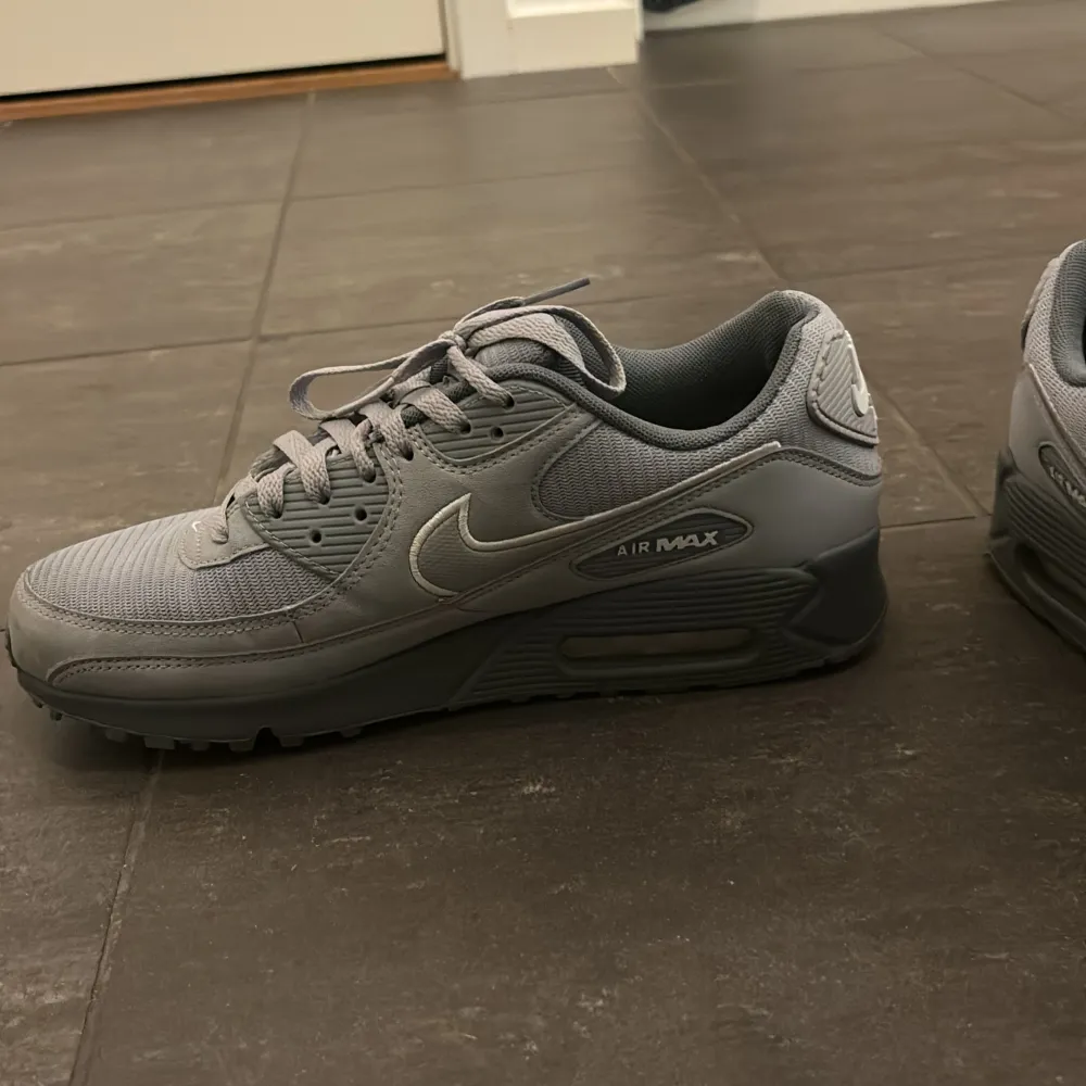 Säljer ett par grå Nike Air Max sneakers i mycket bra skick. De har blivit använda Max 10 gånger.  De har en stilren design med snörning och en bekväm sula. Perfekta för både vardag och träning. Storlek är inte specificerad, men de ser ut att passa en normal passform.. Skor.