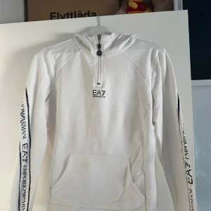 EA7 Armani vit hoodie  - Säljer en snygg vit hoodie från Emporio Armani EA7. Säljer den pga av storlek, inga skador eller något liknande hör av er vid frågor, priset kan diskuteras vid snabb affär