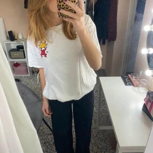 Vit t-shirt med färgglatt tryck - Säljer en vit t-shirt med ett coolt tryck av två figurer i rött och gult. Perfekt för en avslappnad stil och passar bra till jeans eller shorts. T-shirten har en normal passform och korta ärmar. 🩷