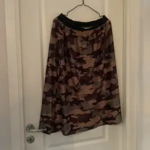 Säljer en cool camouflage kjol i normal passform. Perfekt för en avslappnad och trendig look. Kjolen har ett elastiskt midjeband för extra komfort. Passar bra till både vardag och festliga tillfällen.