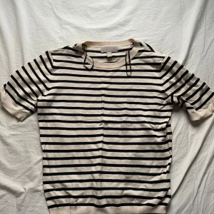 Randig kortärmad tröja från H&M - Säljer en superfin randig tröja från H&M i storlek XS. Den är beige med svarta ränder och har korta ärmar. Perfekt för vår och sommar! Tröjan är i mycket bra skick och gjord av mjukt material. Passar både till jeans och kjol. 🌟