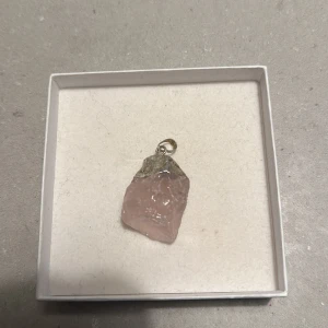 Rosa kvarts hänge - Säljer ett vackert rosa kvarts hänge med en silverfärgad infattning. Perfekt för att göra ditt eget halsband eller som en personlig present. Hänget har en rå och naturlig form som ger en unik form.