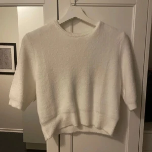 Vit fluffig tröja - Mysig vit tröja i fluffigt material, perfekt för kyliga dagar. Den har trekvartsärmar och en enkel design som gör den lätt att matcha med olika outfits. Perfekt för både vardag och mysiga hemmakvällar.