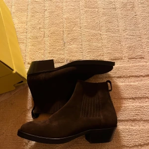 J Lindeberg jesse western suede boot  - Snygga bruna j lindeberg boots i mocka, perfekta för höst och vinter. De har en klassisk design med elastiska paneler på sidorna för enkel på- och avtagning. Skorna har en låg klack och är i mycket bra skick. Perfekta för både vardag och fest! Helt nya inte testade. Nypris 3600 och storlek 43