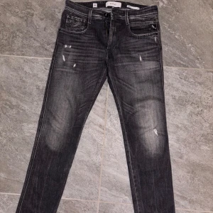 Grå jeans från Replay - Säljer ett par snygga grå jeans från Replay i modellen Anbass. De har en cool slitningseffekt och klassisk femficksdesign. Perfekta för både vardag och fest! 🖤