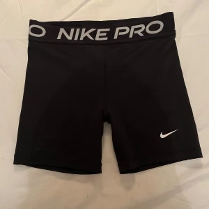 Svarta träningsshorts från Nike Pro - Säljer ett par svarta Nike Pro träningsshorts i storlek XL. De är tillverkade i Dri-FIT-material som håller dig torr och bekväm under träningen. Shortsen har en elastisk midja med Nike Pro-logga och en tight passform. Perfekta för gymmet eller löprundan!