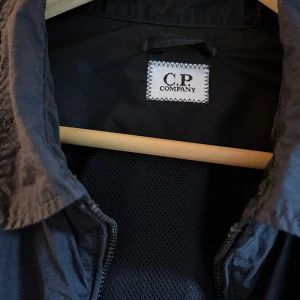 Svart jacka från C.P. Company - Säljer en snygg svart jacka från C.P. Company. Den har en dragkedja framtill och långa ärmar. Perfekt för höst och vår. är i mycket bra skick. Passar både till vardags och lite mer uppklädda tillfällen.