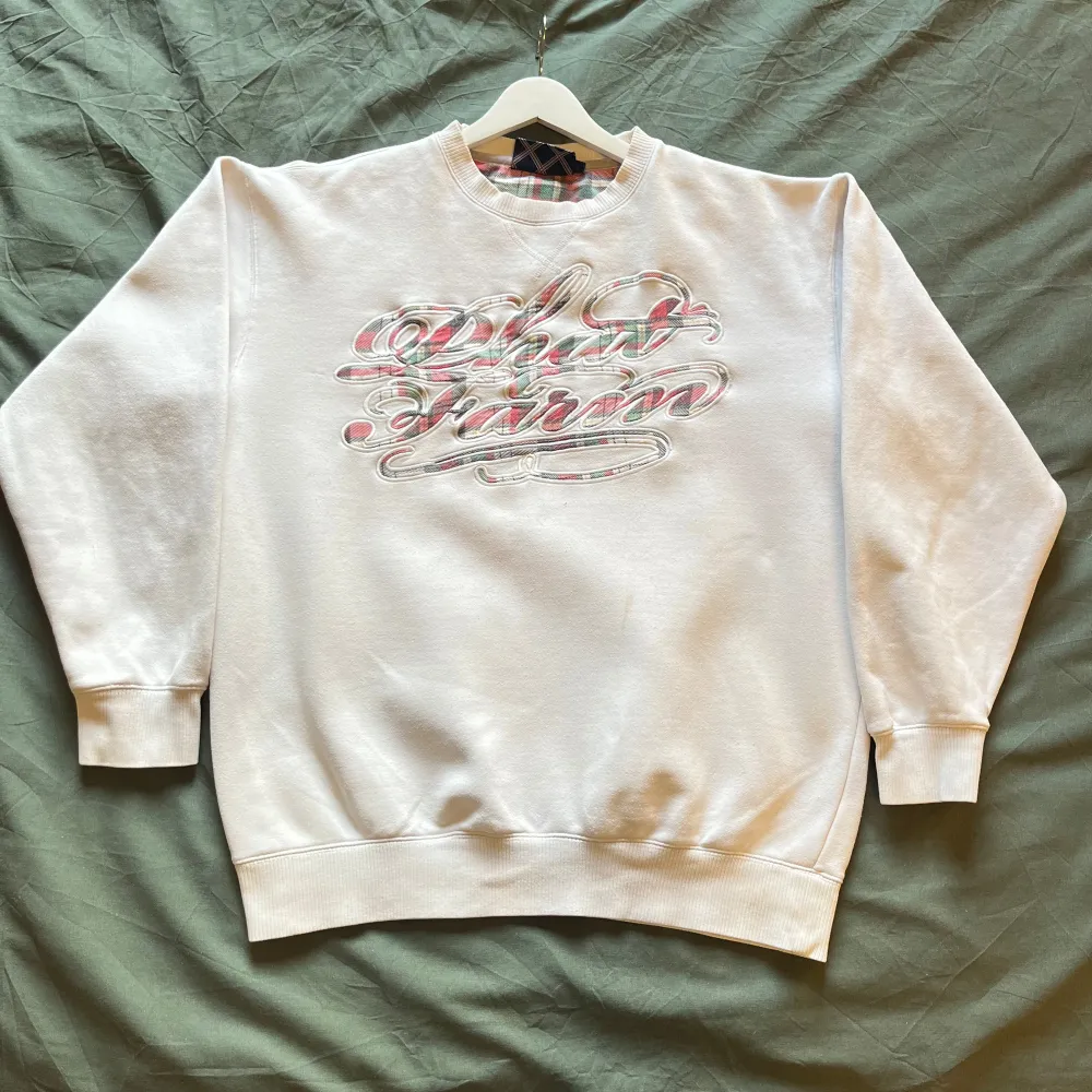 Vit sweatshirt med grönt och rött broderi från Phat Farm. Bra skick (se en liten fläck och reva på sista bilden). Oversized med snygg 90-talig passform. 80% bomull & 20% polyester. Jag på bilden är ca S och 175cm lång. . Tröjor & Koftor.