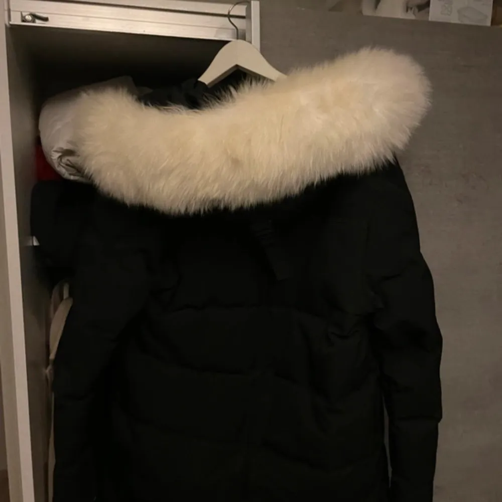 Säljer en snygg svart dunjacka från Kenzo med en fluffig vit pälskrage. Jackan har en dragkedja framtill och är perfekt för kalla vinterdagar. Den är i mycket bra skick och har en stilren design som passar till det mesta. Perfekt för både vardag och fest!. Jackor.