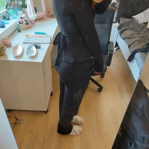 Svart ribbad topp med knytband från nelly - Säljer en snygg svart ribbad topp med långa ärmar och v-ringning. Toppen har ett knytband i midjan som ger en fin passform. Perfekt för både vardag och fest!