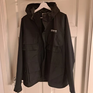 Svart jacka från Adidas Adventure - Säljer en svart jacka från Adidas Adventure i mycket bra skick. Det står M i storlek men jag skulle säga att det är mer som L, Den har en huva och flera fickor.