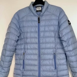 Ljusblå dunjacka från McKinley - Säljer en snygg ljusblå dunjacka från McKinley i mycket bra skick. Jackan har en dragkedja framtill och två praktiska fickor med dragkedjor. Perfekt för kyliga dagar och ger en stilren look. Passar både till vardags och lite finare tillfällen.