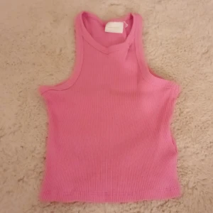 Rosa ribbad linnetopp - Säljer en söt rosa ribbad linnetopp i mycket bra skick. Perfekt för sommardagar eller som ett lager under en jacka. Toppen är ärmlös och har en bekväm passform. Passar både till vardags och festliga tillfällen.