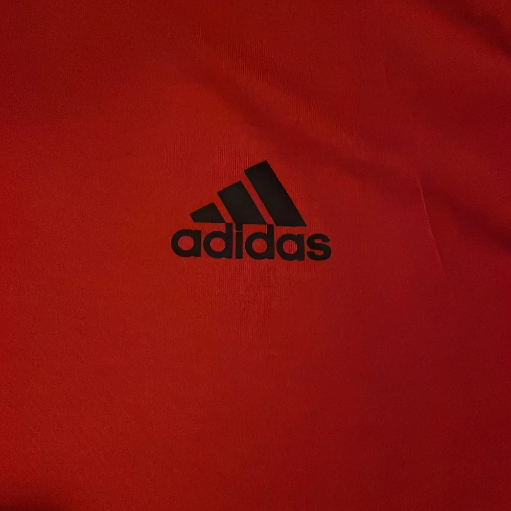 Säljer en snygg röd t-shirt från Adidas i modellen Freelift. Den har en normal passform och är kortärmad, perfekt för träning eller vardagsbruk. Tillverkad i Climalite-material som håller dig torr och bekväm. Adidas-loggan i svart på bröstet ger en sportig touch. . T-shirts.