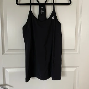 Svart linnetopp från Adidas - Säljer en svart linnetopp från Adidas i storlek S. Perfekt för träning med sitt Climalite-material som håller dig sval och torr. Den har smala axelband och en stilren design med Adidas-loggan på bröstet. Passar perfekt för gymmet eller löprundan!