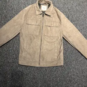 Säljer en snygg beige mockajacka från Jack & Jones i storlek S. Jackan har en dragkedja framtill och två bröstfickor med lock. Perfekt för höst och vår med sin stilrena design och mjuka material. Hör av er vid minsta fundering 🍾