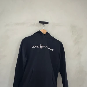 Svart hoodie från Sail Racing - Säljer en svart hoodie från Sail Racing i mycket bra skick. Den har en klassisk passform med en stor logga på bröstet. Perfekt för höst och vinter, och den är superbekväm att ha på sig. Passar både till vardags och chillkvällar. 🖤