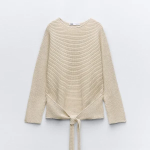 Beige stickad tröja från Zara - Säljer en superfin beige stickad tröja från Zara, har bara använt den 2 gånger. Den har långa ärmar och en unik knytning framtill eller baktill som ger en snygg detalj. Perfekt för höst och vår när det är lite kyligt ute. Tröjan är i nyskick och passar till både jeans och kjol. 🧶✨