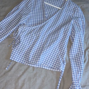 Rutig topp från zara med knytdetalj - Jag säljer denna blåvita blus från zara i storlek S. Endast provad så är i bra skick. Den har en knytdetalj. Supersöt till allt!!