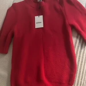 Röd tröja från Addax - Säljer en snygg röd tröja från Addax i mycket bra skick. Den har en enkel design med ribbstickade muddar vid ärmslut och nederkant. Perfekt för både vardag och fest! 🔥