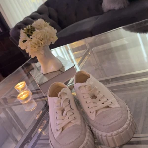 Vita sneakers med platåsula - Säljer ett par snygga vita sneakers i mycket bra skick. De har en cool platåsula och klassisk snörning. Perfekta för både vardag och fest! Passar till allt och ger en stilren look.
