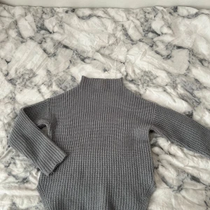 Grå stickad tröja - grå stickad tröja i storlek 146/152 för åldern 11-12 år. Tröjan har långa ärmar och en lite hög krage som håller dig varm. Från Cubus. 