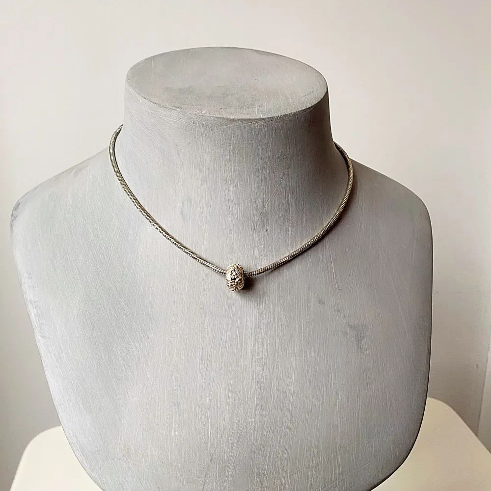 Säljer ett stilrent halsband i silverfärg med en unik, dekorativ pärla i mitten. Halsbandet har en smidig kedja och justerbar längd för perfekt passform. Perfekt för både vardag och festliga tillfällen. Ett måste för den som älskar minimalistisk design!. Asusteet.