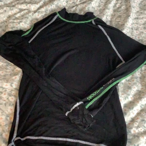Svart långärmad tröja från Walking - Säljer en svart långärmad tröja från Walking i storlek S. Perfekt för utomhusaktiviteter med gröna och vita sömmar som ger en sportig look. Tröjan kan även användas som underställ. Materialet är mjukt och bekvämt, idealiskt för höst- och vårpromenader. 