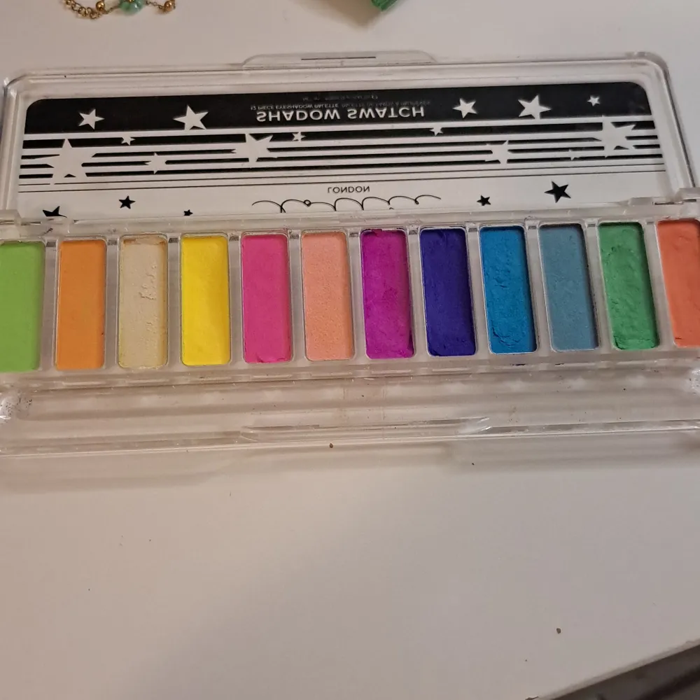 Säljer en superfin ögonskuggspalett 'Shadow Swatch The Rainbows' från Lottie London. Paletten har 12 färgglada nyanser, perfekt för kreativa och färgglada looks. Kommer i en praktisk plastförpackning med stjärndetaljer. Perfekt för både vardag och fest!. Skönhet.