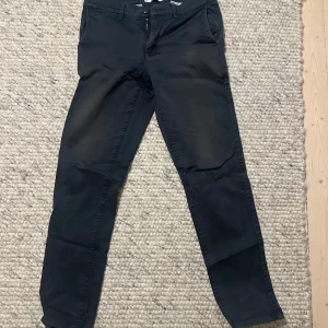 Mörkblå  byxor från These Glory Days - Säljer ett par stilrena mörkblå byxor från These Glory Days i storlek 48. Byxorna har en klassisk design med knapp och dragkedja framtill. Perfekta för både vardag och festliga tillfällen. De är i mycket bra skick och redo för en ny ägare!