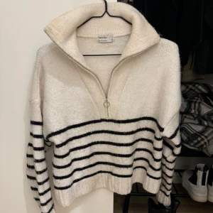 Randig tröja från Bershka - Säljer en superfin randig tröja från Bershka i beige och svart. Den har en dragkedja framtill och en hög krage som ger en mysig känsla.
