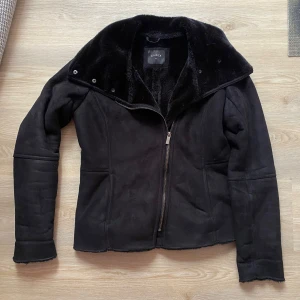 Svart jacka från Lindex - Säljer en snygg svart jacka från Lindex i storlek M. Den har en mjuk och varm fuskpäls på insidan och en dragkedja framtill. Perfekt för kyliga höst- och vinterdagar. Jackan är i mycket bra skick och har en stilren design som passar till det mesta. 🖤