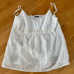 Vit babydolltopp - Vit, babydoll topp med pärlor. Perfekt att ha till vardags eller på fest. Osäker på storlek men skulle säga L. Toppen har ett litet rosa streck men det syns knappt. Pris kan diskuteras.