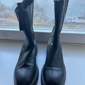 Svarta boots och Nike sneakers - Säljer ett par svarta boots(Duffy) i skinn. Stl. Perfekta för höst och vinter. Används 2ggr. Dessutom ett par Nike air stl 39 sneakers i svart och beige med snörning och en cool camouflagedetalj, idealiska för vardagsbruk. För Duffy 300kr. Nike air 400kr