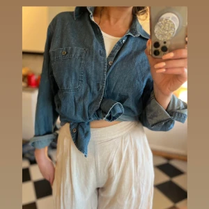 Simin T vintage Armani skjorta - En Simin T Armani vintage skjorta i jeansblå denim med långa ärmar och en ficka på bröstet. Knappar framtill och är tillverkad i en mjuk bomullsdenim. Medium. Väl använt skick. 100% bomull.