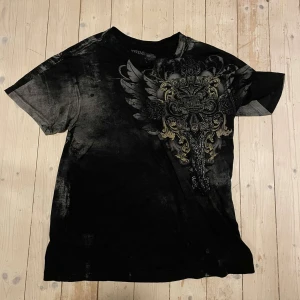Xtreme couture tisha - Riktigt sällsynt affliction type tshirt. Storlek xl men passar mer som L tycker jag. Kontakta gärna vid eventuella frågor eller om du vill ha fler bilder.